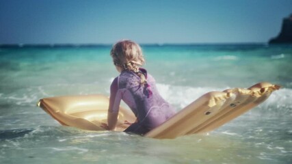 A little girl enjoys the waves of the Mediterranean Sea on an air mattress.