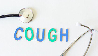 The word cough in wooden letters and with a stethoscope next to it on a white background. Conceptual for healthcare, hospitals, clinics and medical business.