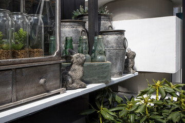 Stone figurine of a hare, aluminum cans, vases, rhododendrons in terracotta pots, glass jars with artificial succulents