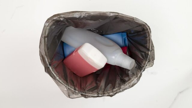 Garbage bag is filling in with empty plastic cosmetics bottles. Stop motion animation. 
