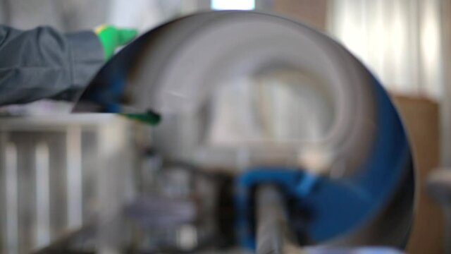 The machine bends a sheet of stainless steel into a pipe. A four-roll plate bending machine in a ventilation and gutter manufacturing plant. Tools and equipment for bending sheet metal.