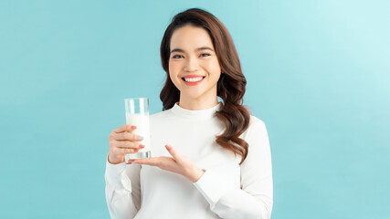Portrait young asian woman drinking milk from the glass isolated over blue background