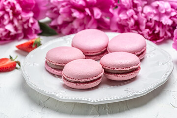 Obraz na płótnie Canvas Elegant sweet macarons and Pink peony rose flowers, French delicate dessert for Breakfast in the morning light
