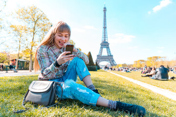Happy girl using phone in Paris with Eiffel Tower on background