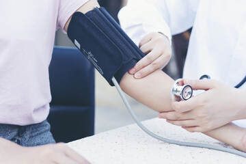 Female doctor holding back to measure patient's blood pressure