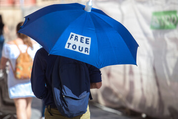 Male free tour guide with blue umbrella