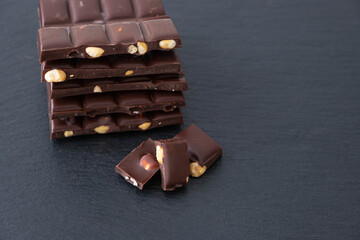 dark chocolate bars with hazelnuts lie on black background