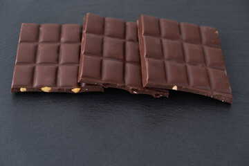 three bars of dark chocolate with hazelnuts lie