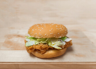 Close up Burger with crispy fried chicken and fresh Iceberg lettuce on wooden plate.