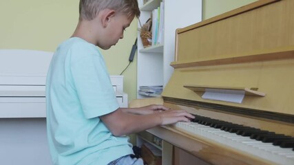 Boy looking down, practicing piano with sheet music, skill, talent, musical