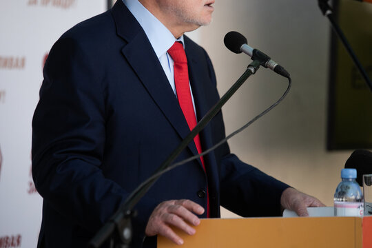 Businessman giving interview at table with microphones, closeup. Journalist conference