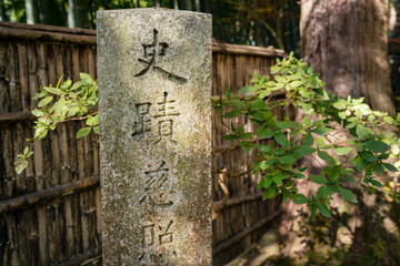 A stone column in a corner of Japanese garden in Kyoto with Japanese letters on it.