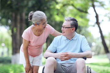 The old man pushes his wife in a wheelchair