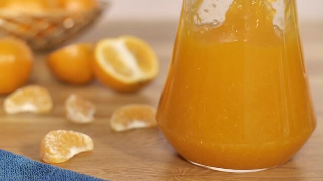 Orange slices splashing in a transparent jug filled with nutritional orange juice. Closeup shot of delicious juicy orange halves and slices kept with its liquid form on a wooden table - healthy tro...