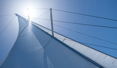 Yacht sails on clear blue sky background. Sailing with the wind at open sea ocean, summer holidays