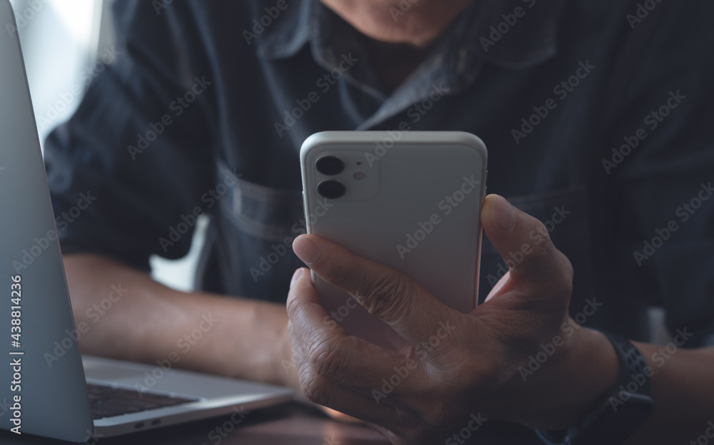 Aufkleber man using mobile phone and working on laptop computer from home office, close up