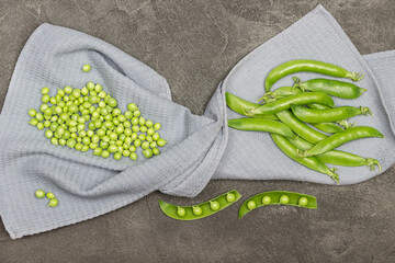 Pods of green peas and green peas on gray napkin