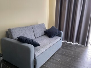 grey sofa with pillows and dark curtain
