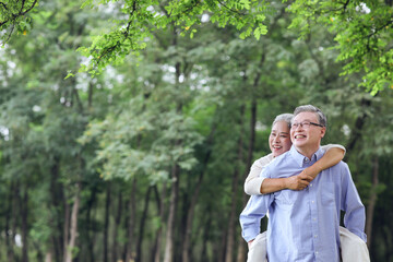 The old man is looking at the scenery with his wife behind his back in the park