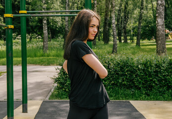 a girl in black performs a sports exercise side turns on the playground
