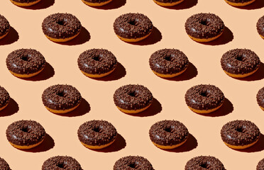 Pattern of chocolate donuts on orange pastel background