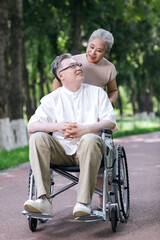 The old man pushes his wife in a wheelchair