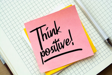 Closeup Pink Sticky Note paste it in a notebook setting an appointment. The words Think positive...