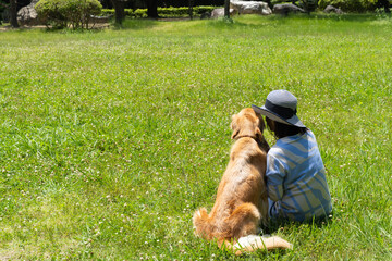 ひそひそ話してるゴールデンレトリーバーと女性の後ろ姿

