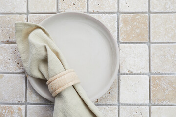 Stylish serving on a travertine mosaic background. Linen napkin on plate. Top view