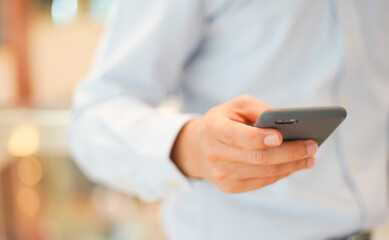 Smartphone Mobile phone hold touch in a Asian people hand in coffee shop restaurant waiting for friends with hand touching a Smart Phone, Technology smartphone communication Background Concept