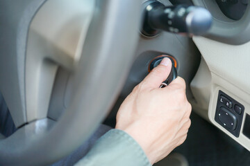 Closeup shot of Asian man hand inserting key in igniting car for starting / shutting down car...