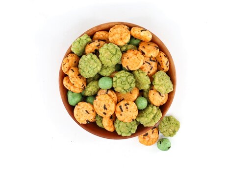 Small rice crackers and battered peanuts with spicy wasabi flavor in a bowl. White background.