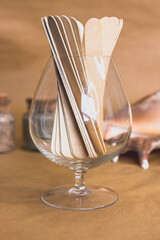 Wax wooden spatulas in a glass on brown background and nautical theme. Wax epilation tools. Self...
