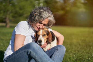 Adult woman with her Beagle dog sitting on the grass