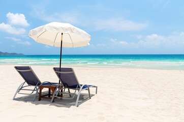 Beach chairs with white umbrella and beautiful sand beach in Koh Samui, Thailand.