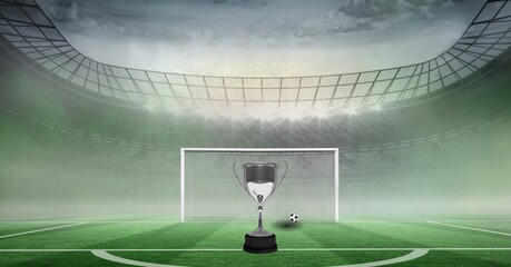 Composition of gold cup and football on football pitch and sports stadium