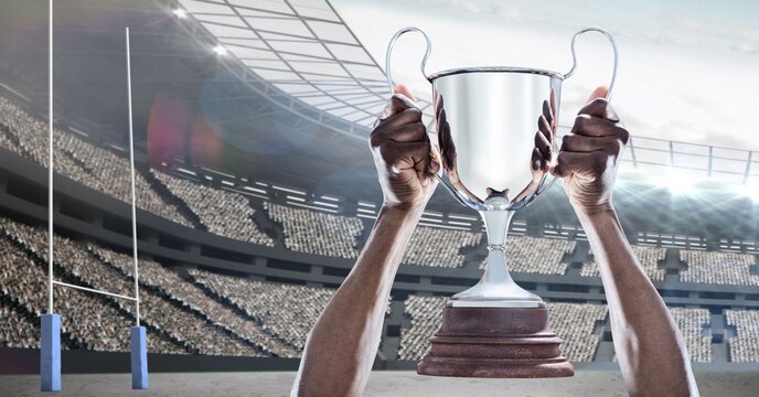 Composition of male rugby player celebrating victory, holding trophy at stadium