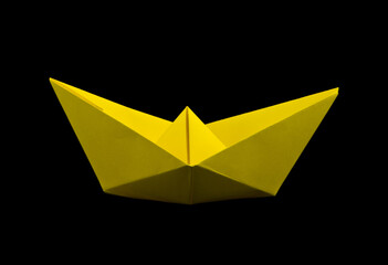 Yellow paper boat isolated on a black background.