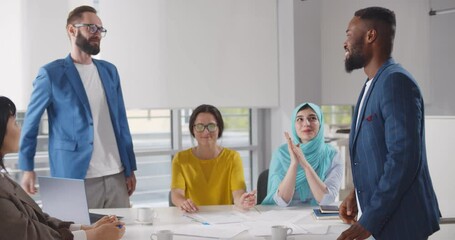 Diverse business people closing deal and shaking hands after negotiation meeting in office