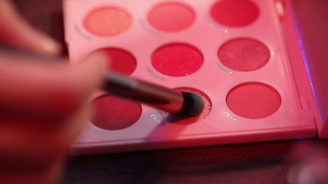 cropped view of woman applying eye shadow with shimmer on cosmetic brush