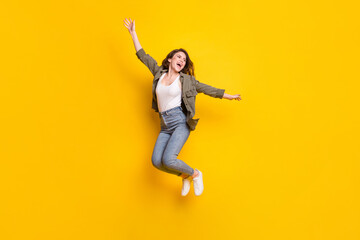 Fototapeta na wymiar Full body photo of carefree young girl jump high open mouth smile look empty space isolated on yellow color background