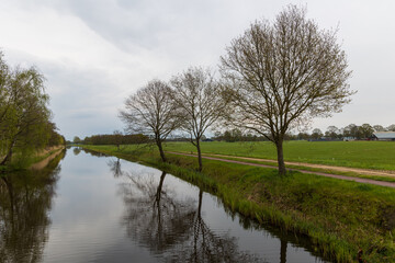 Fototapeta na wymiar Canal landscape scenery with tree silhouettes