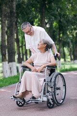 Obraz premium The old man pushes his wife in a wheelchair