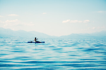 Woman silhouette rowing a kayak alone on blue waters of Ohrid lake in North Macedonia