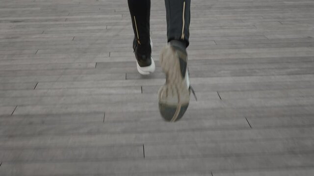 Slim female legs in leggings and sneakers running on street