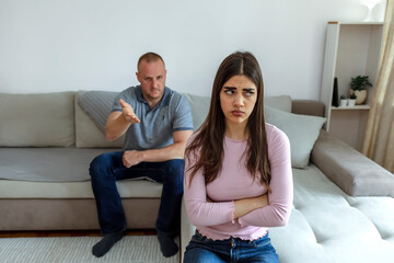 Cropped shot of a couple having a disagreement at home. Young couple in quarrel at home. Sad young Caucasian woman sitting on sofa with boyfriends. Frustrated young couple having marriage problems.