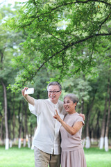 Obraz premium Happy old couple take selfie with mobile phone in park