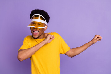 Portrait of attractive funky cheerful guy wearing sun hat having fun dancing isolated over violet purple color background