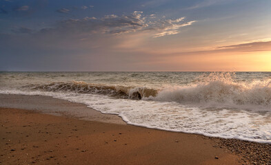 Green blue sea splashing waves backlit by setting sun in front of beautiful sunset sky background. Travel and tourism concept. Nature background. Copy space.