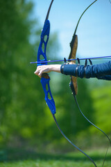 professional archer shooting with modern longbow at forest 